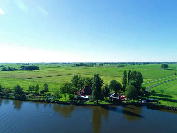Luchtfoto van het terrein van Vrijzicht, omringd door weiland en water